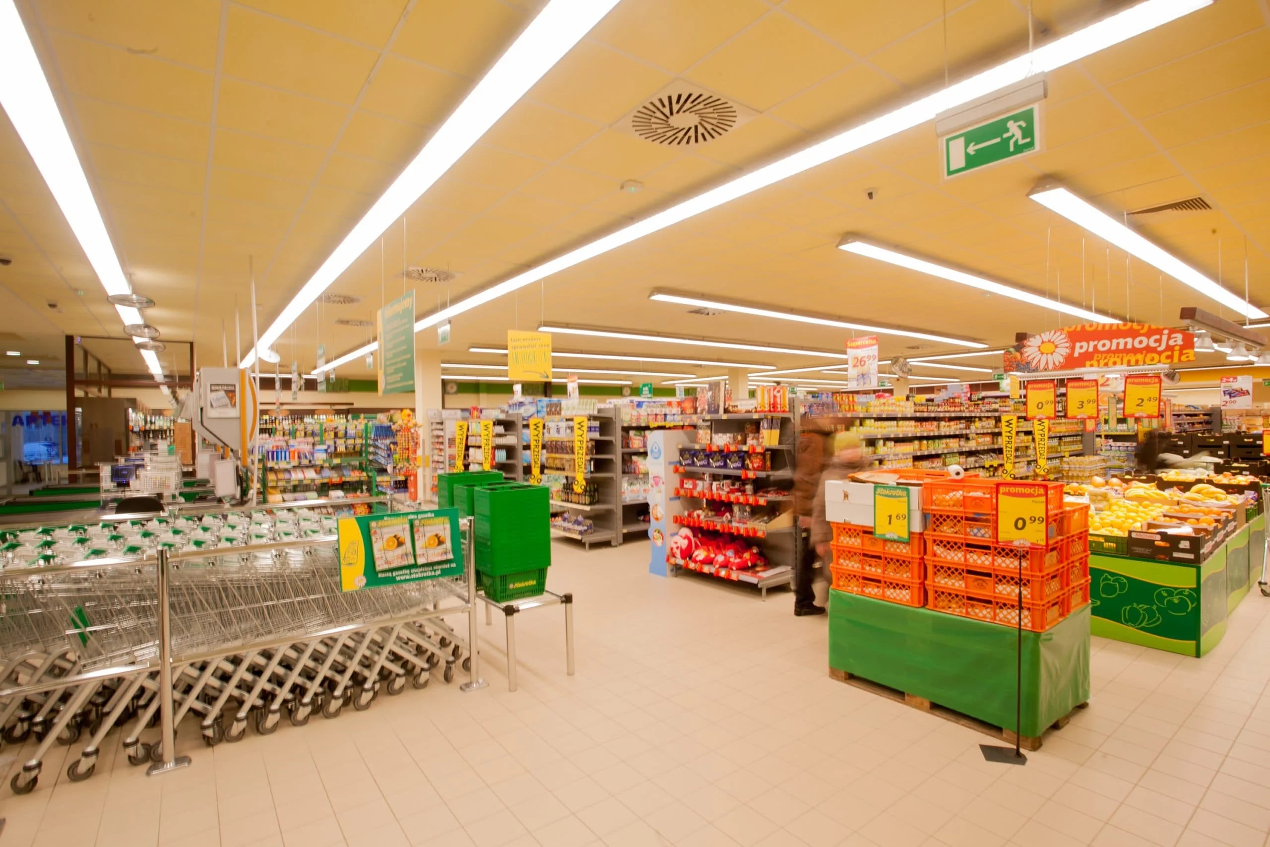 Oświetlenie LED skierowane wzdłuż alejek z chłodniami i regałami w sklepie Stokrotka