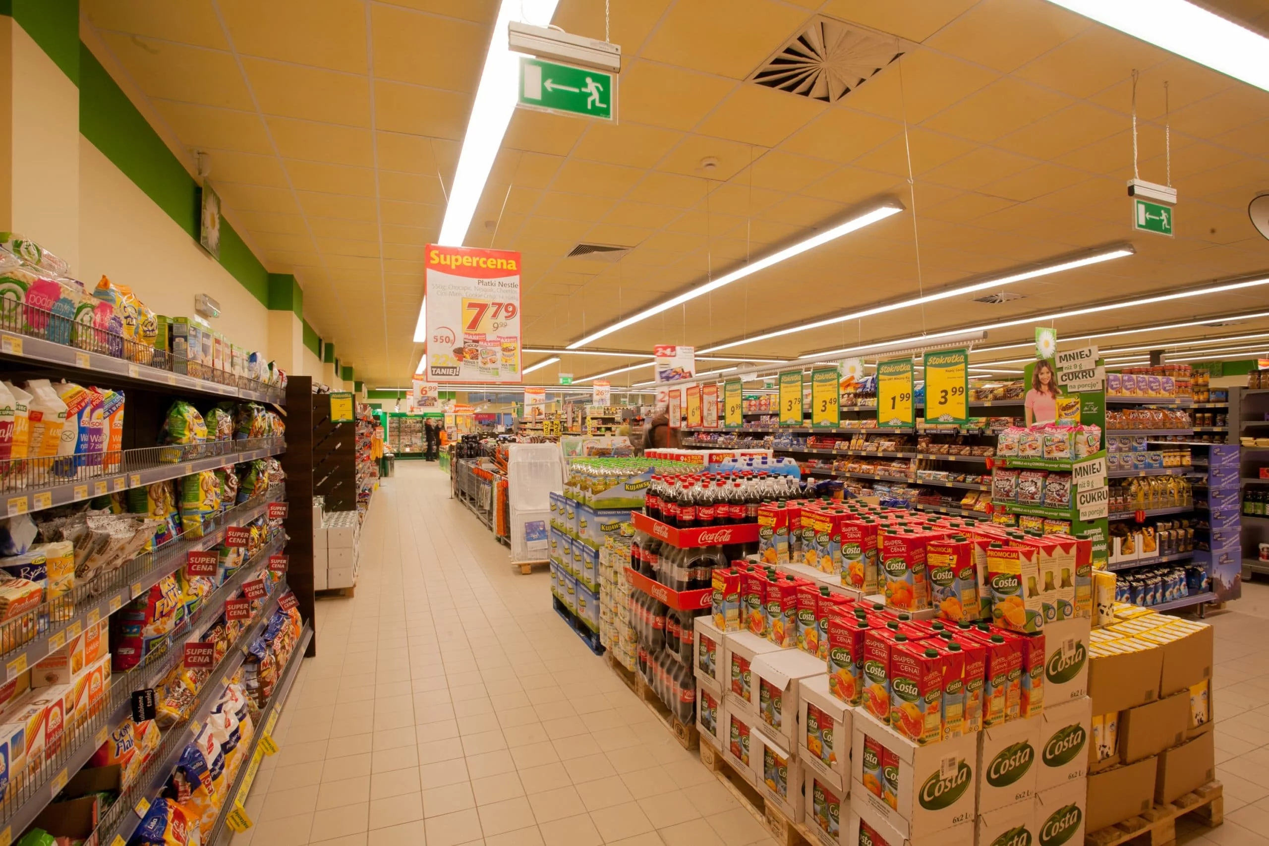 Oświetlenie LED skierowane wzdłuż alejek z chłodniami i regałami w sklepie Stokrotka