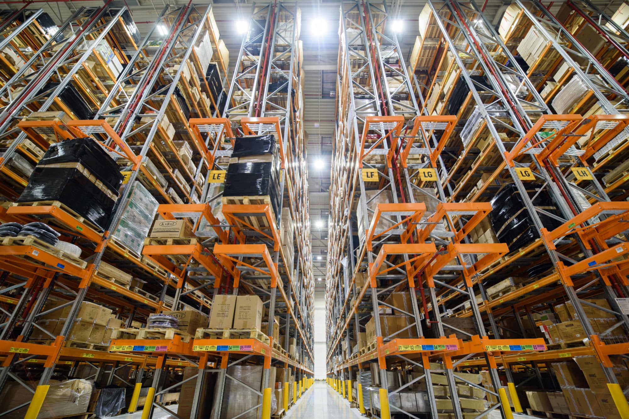 Korytarz magazynu wysokiego składowania firmy Kramp oświetlony lampami LED